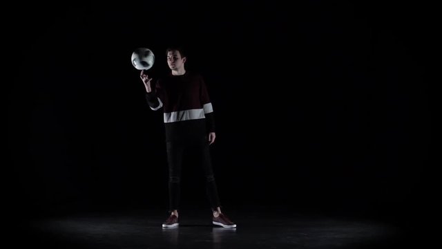 Slow motion of professional football player in casual jumper spinning ball