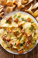 Italian ravioli with chanterelles and parmesan cheese close-up on a plate. Vertical top view