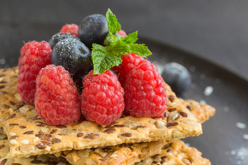 Cookies with whole grains. Raspberry and blueberry berries with icing sugar on top. black background.