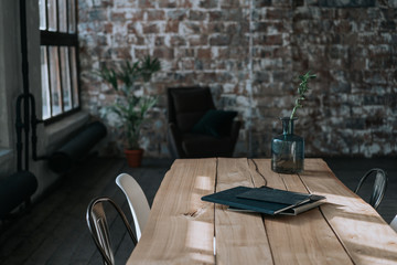A simple loft-style interior with brick walls, a large window, a wooden desk and a tropical palm tree