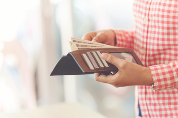 Girl with brown wallet full of money, female hands close-up hold a black purse in which dollars lie, Wallet Hands Credit Card Mobile Concept, shopping online concept