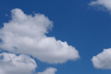 Blue sky background with white clouds. Cropped shot, horizontal, free space. Concept of natural beauty.