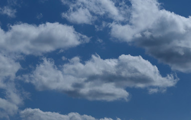 Blue sky background with white clouds. Cropped shot, horizontal, free space. Concept of natural beauty.