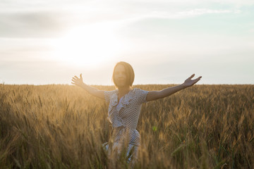 Middle age woman in a dress on a wheat field at sunset. Freedom, naturalness, nature concept. © Konstiantyn Zap