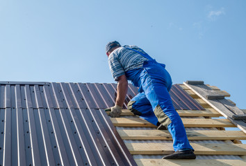 an employee performs roofing work, for fixing sheeting with self-tapping screws