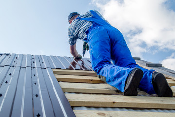 an employee performs roofing work, for fixing sheeting with self-tapping screws