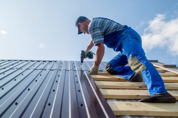an employee performs roofing work, for fixing sheeting with self-tapping screws