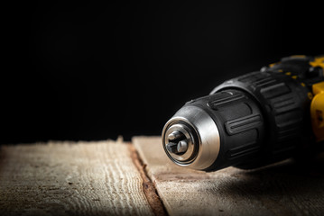 Electric drill closeup on a black background with wood and drills. Electrical tools. Hand battery...