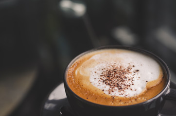 close up modern hot black coffee the cappuccino on dark background with coffee bubble foam pattern and texture in black cup looking and feel so delicious on glasses table in coffee shop.