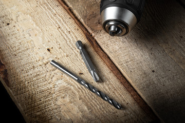 Electric drill closeup on a black background with wood and drills. Electrical tools. Hand battery screwdriver.