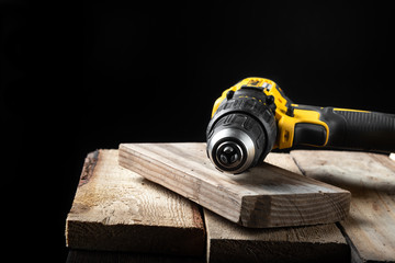 Electric drill closeup on a black background with wood and drills. Electrical tools. Hand battery...