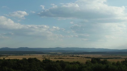 Flying from the field over forest and the mountains, hills.