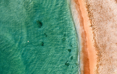 Sandy seashore with turquoise green sea water. Small waves on the beach.