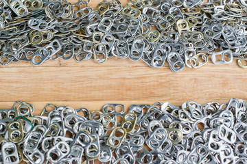aluminum pull tabs on wooden table to recicle,copy space for text.