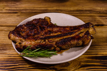 Plate with roasted ribeye steak on wooden table