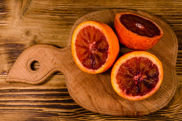 Cutting board with halved sicilian oranges on a wooden table. Top view