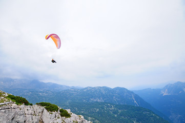 Paraglider flying over mountains in summer day.