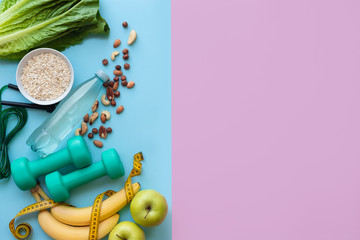 Fitness background with bottle of water, apple, dumbbells, nuts, and tape measure on color table