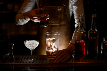 Bartender pours cocktail from vial in glass
