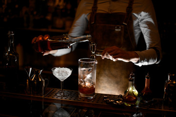 Fototapeta na wymiar Bartender prepares alcohol cocktail using jigger with handle