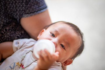 Asian baby girl sucking milk from bottle, Kid drinking milk