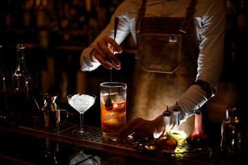 Bartender stirs alcohol cocktail with the spoon