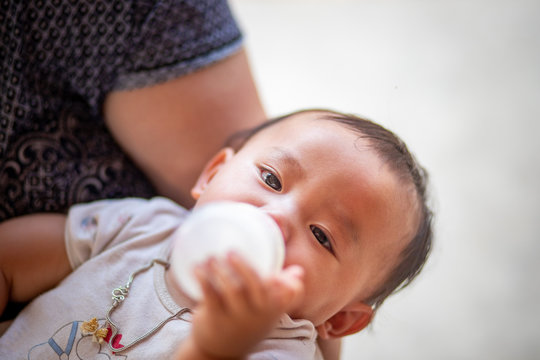 Asian baby girl sucking milk from bottle, Kid drinking milk