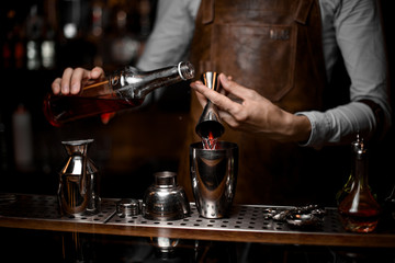 Fototapeta na wymiar Bartender pouring alcohol from jigger to shaker