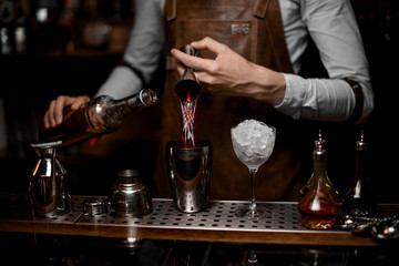 Bartender pours drink from jigger to shaker