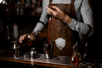 Fototapeta na wymiar Bartender pouring drink from jigger to shaker