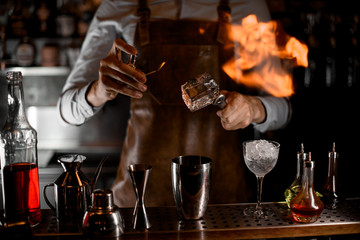Bartender fires up an ice cube in tongs