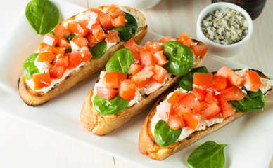 Tomato and cheese fresh made bruschetta. Italian tapas, antipasti with vegetables, herbs and oil on grilled ciabatta and baguette bread. Sandwich.