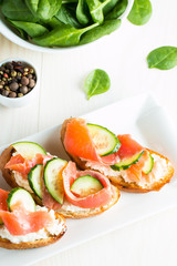 Salmon, cucumber and cream cheese bruschetta. Italian tapas, antipasti with vegetables, herbs and oil on grilled ciabatta and baguette bread. Sandwich.