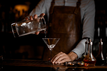 Bartender pouring an alcohol cocktail from jar