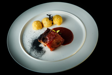 big piece of delicious meat with potato balls and red sauce
