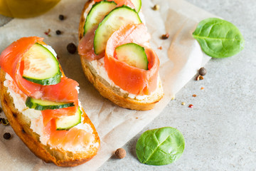 Salmon, cucumber and cream cheese bruschetta. Italian tapas, antipasti with vegetables, herbs and oil on grilled ciabatta and baguette bread. Sandwich.
