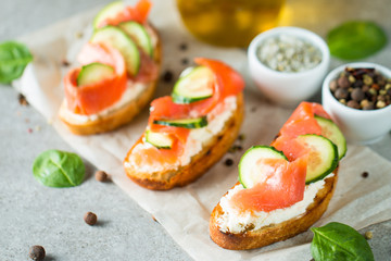 Salmon, cucumber and cream cheese bruschetta. Italian tapas, antipasti with vegetables, herbs and oil on grilled ciabatta and baguette bread. Sandwich.
