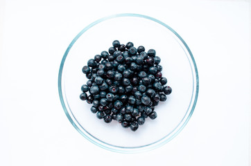  close-up of blueberries with leaves in a plate on a white background