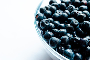  close-up of blueberries with leaves in a plate on a white background