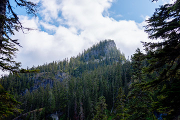 Fluffy white clouds over lone mountain peak in the Alpine Lakes Wilderness. Central Cascade Mountain Range, Washington State, July 2019.