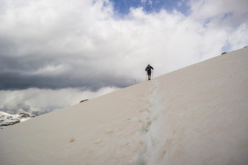 Naklejka na ściany i meble Man walking in the high mountains on the snow with thunderstorm at the horizon. Monte Piz Boè, Sella group in the province of Trento - Italy