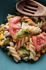 Pasta salad on green plate and rustic wooden table