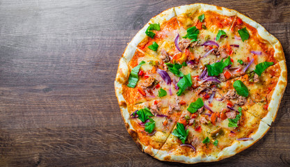 Pizza with Mozzarella cheese, onion,  tuna fish, tomato sauce, pepper, basil. Italian pizza on wooden table background