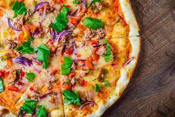 Obraz na płótnie Canvas Pizza with Mozzarella cheese, onion, tuna fish, tomato sauce, pepper, basil. Italian pizza on wooden table background