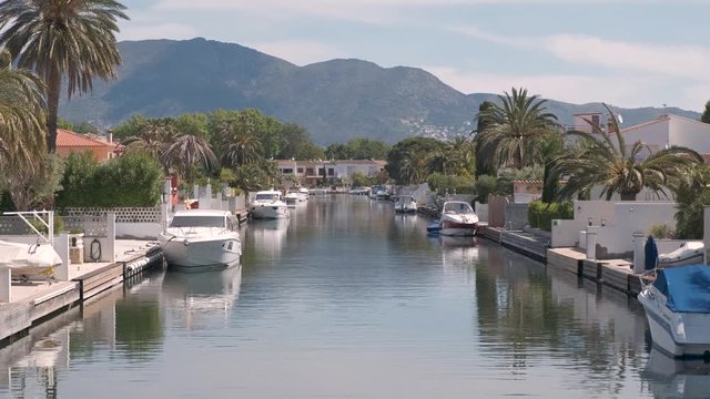 Amazing view on marine canal with boats and houses. Mooring of yachts near a house. Resort cityscape, palm trees, little Spanish Venice, Empuriabrava. Rich Perfect life. Summer, mountains, scenic view