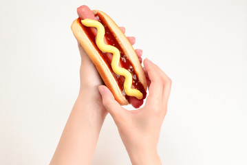 Hot dog in woman hand isolated on white background. Copy space.