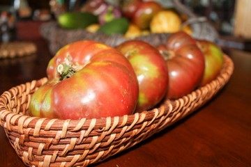 Closeup of Heirloom Tomatoes on Wooden Table and basket, selective focus