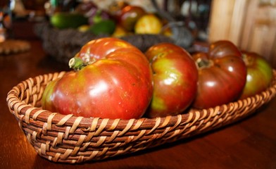 Closeup of Heirloom Tomatoes on Wooden Table and basket, selective focus