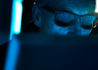 Cyber Crime, reflection in spectacles of virus hacking a computer, close up of face