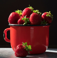 .strawberry in a red mug on a black background